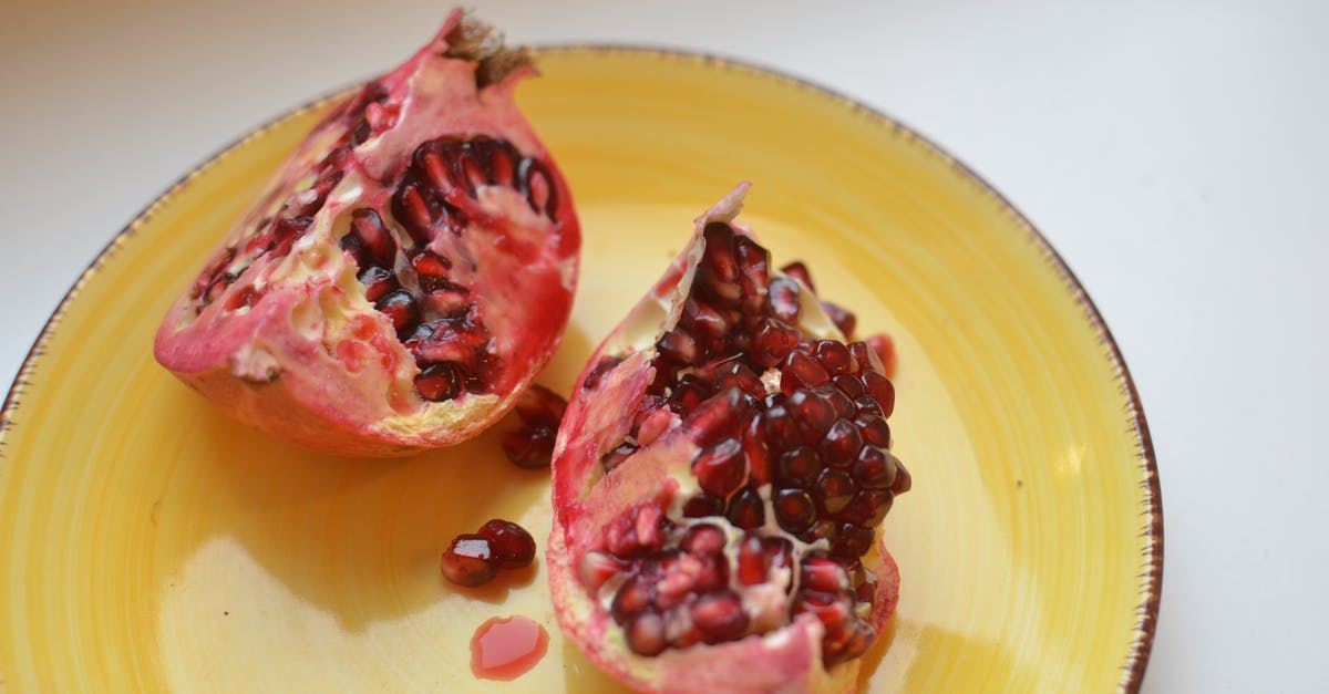 What are ways to extract the juice from a pomegranate? - High angle of sweet halves of healthy pomegranate fruit on light white table