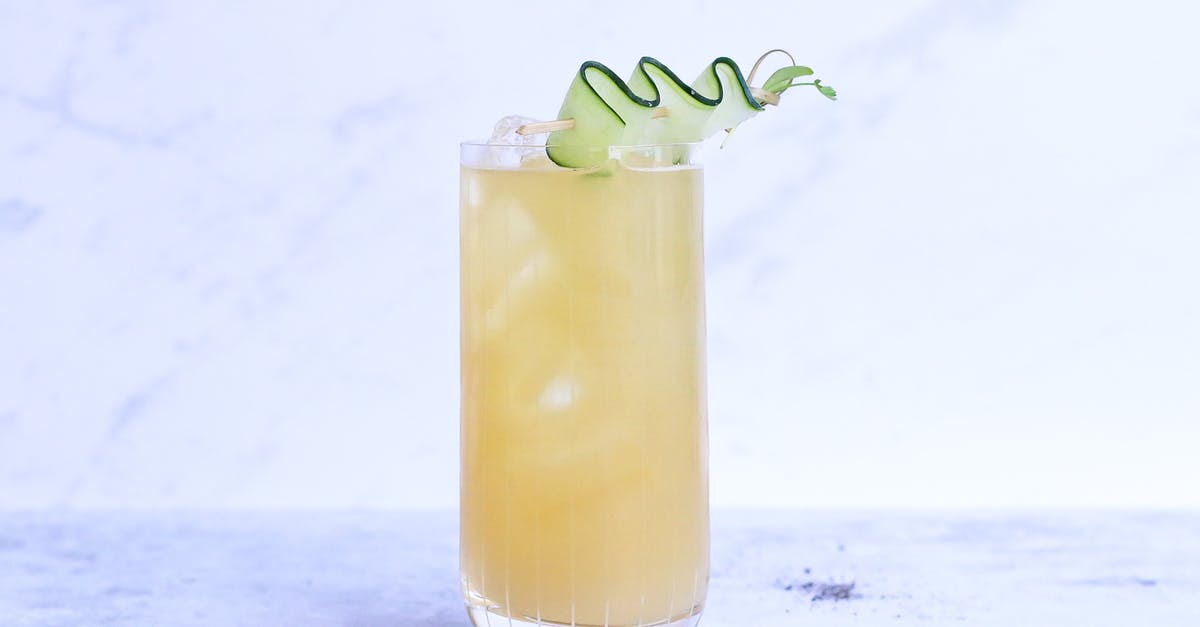 What can I do with ginger syrup? - Glass of yummy sour ginger lemonade garnished with cucumber slice and served on light marble table in studio
