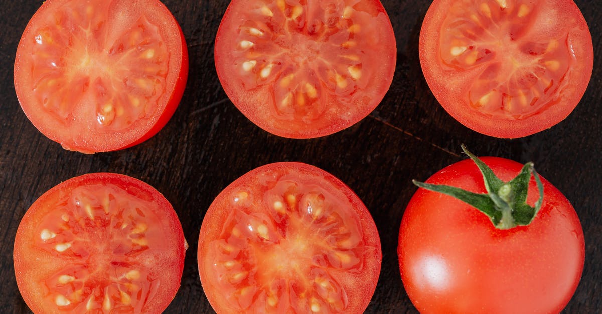 What can I use to replace the tomato juice in gazpacho? - Top view closeup of fresh halves of ripe tomatoes with juice on cut side and whole tomato placed on wooden cutting board