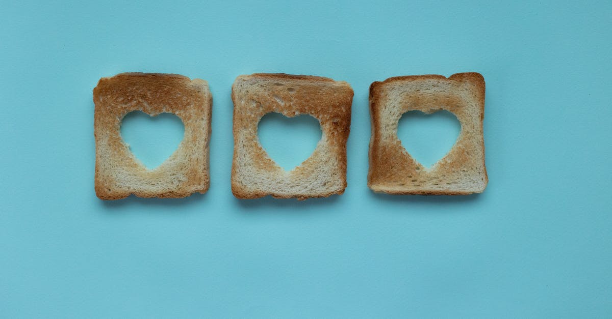 What caused the crust on on the top of my bread to separate from the rest of the loaf? - Top view of crusty pieces from toast bread with cut hearts on blue background