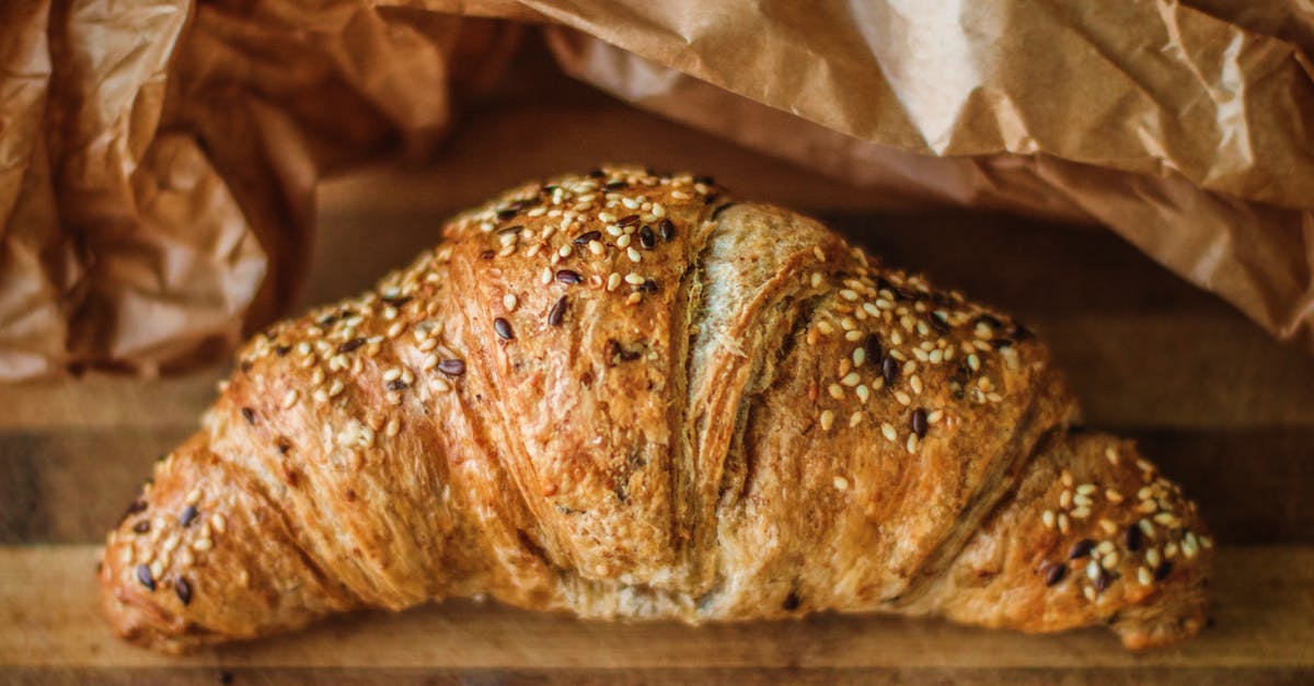 What caused the crust on on the top of my bread to separate from the rest of the loaf? - Top view of delicious crispy croissant with sesame seeds on wooden table near paper bag