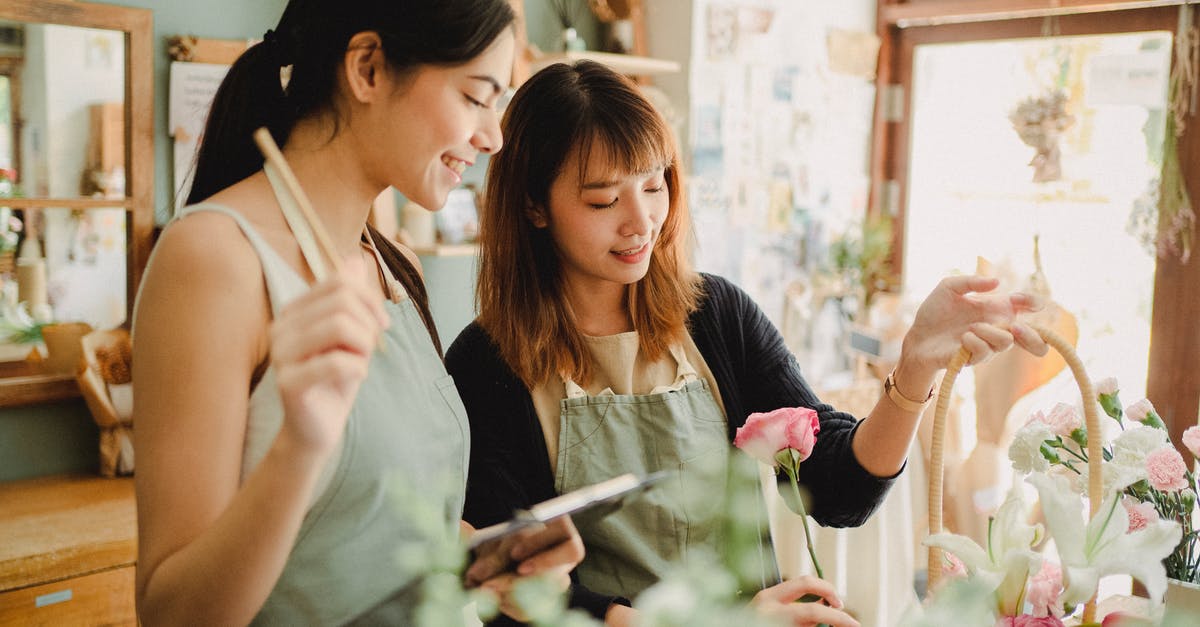 What causes butter to make risotto shiny? - Young glad ethnic female partners creating flower bouquet in basket at table while working in daylight