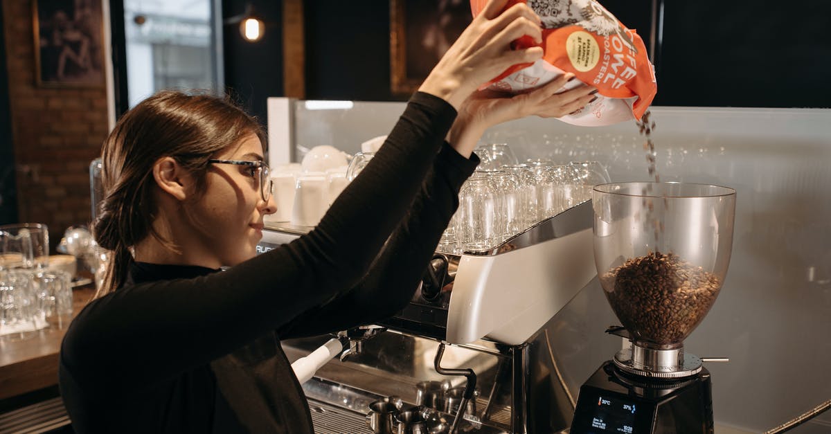 What causes static in a coffee grinder's receptacle? - Woman in Black Long Sleeve Shirt Holding Orange Labeled Pack