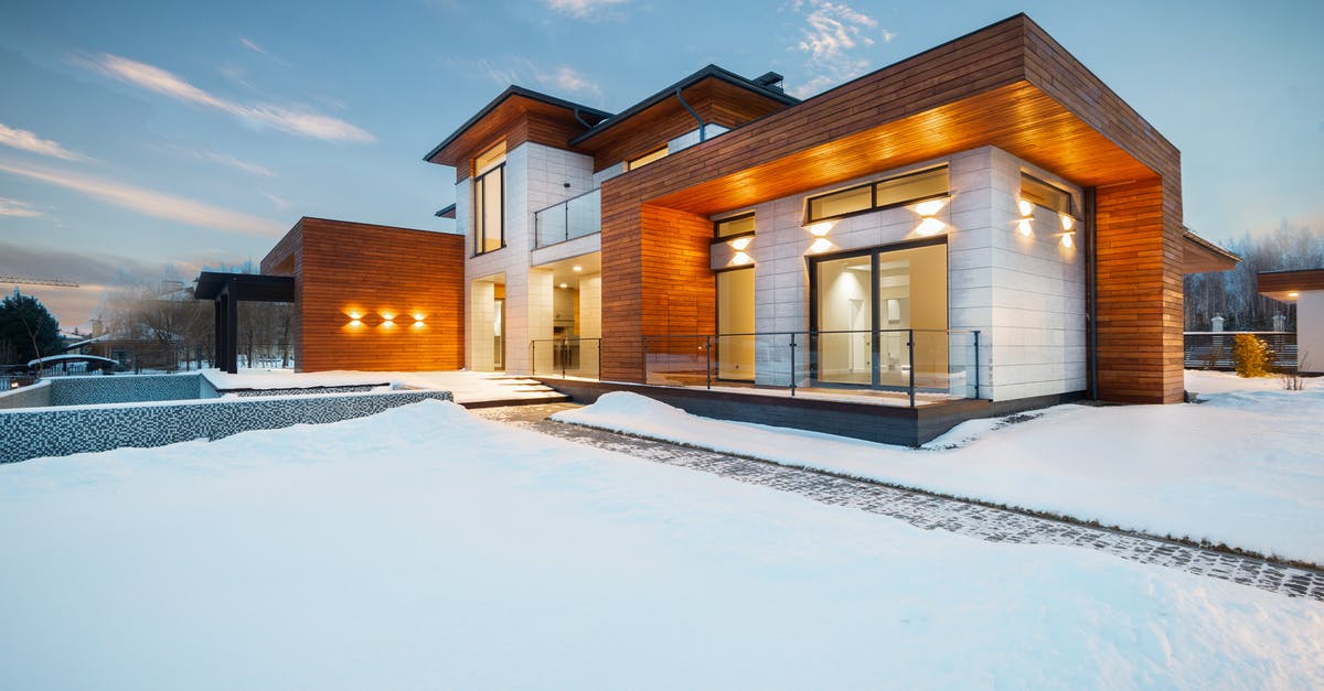 What causes stringy winter squash? - Exterior architecture of private suburban cottage house with stone and wooden facade and large windows overlooking spacious snow covered yard in winter day