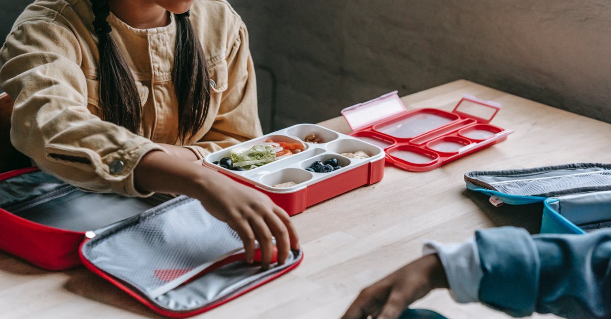 What compound can make crunchy biscuits? - From above of crop anonymous ethnic schoolkids with lunch boxes full of delicious food in classroom