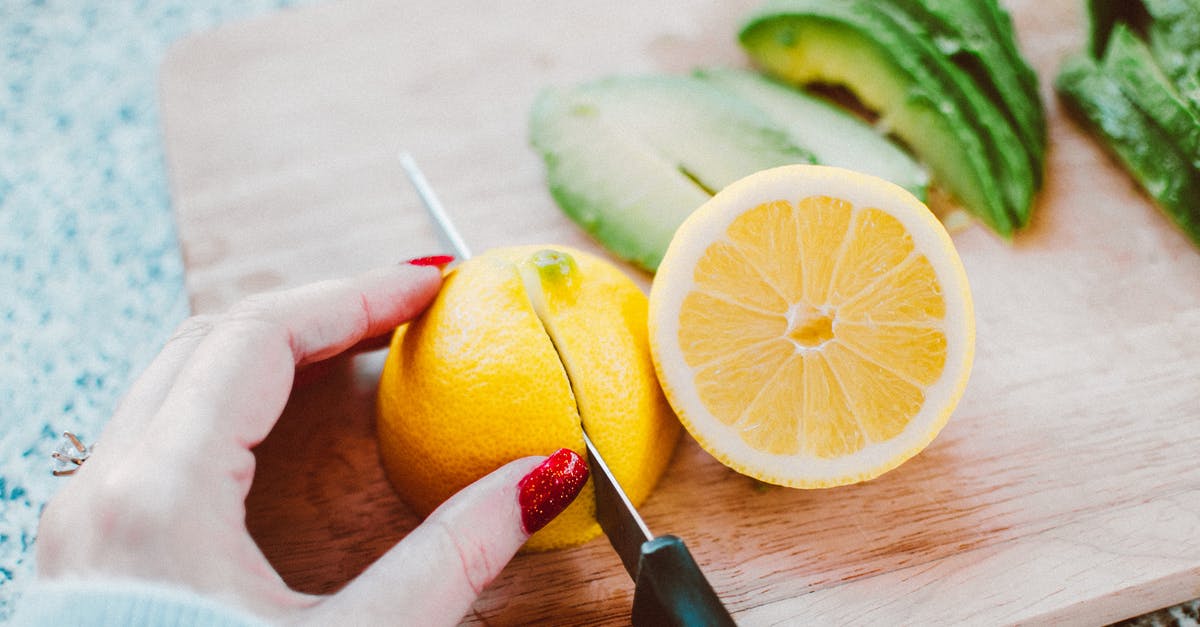 What could be the basic ingredients that potentiate sourness and bitterness? - Person Slicing Lemon on Wooden Chopping Board