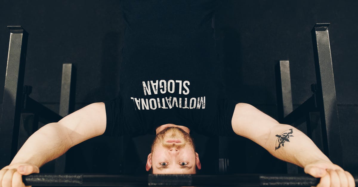 What dishes don't stain with heavy spices? - Bearded sportsman in t shirt with inscription exercising with weight while looking at camera