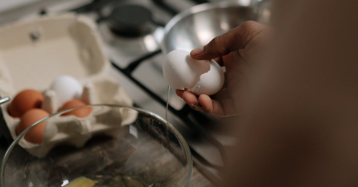 What do I do with one cracked egg? [closed] - A Person Holding a Cracked Egg over a Mixing Bowl