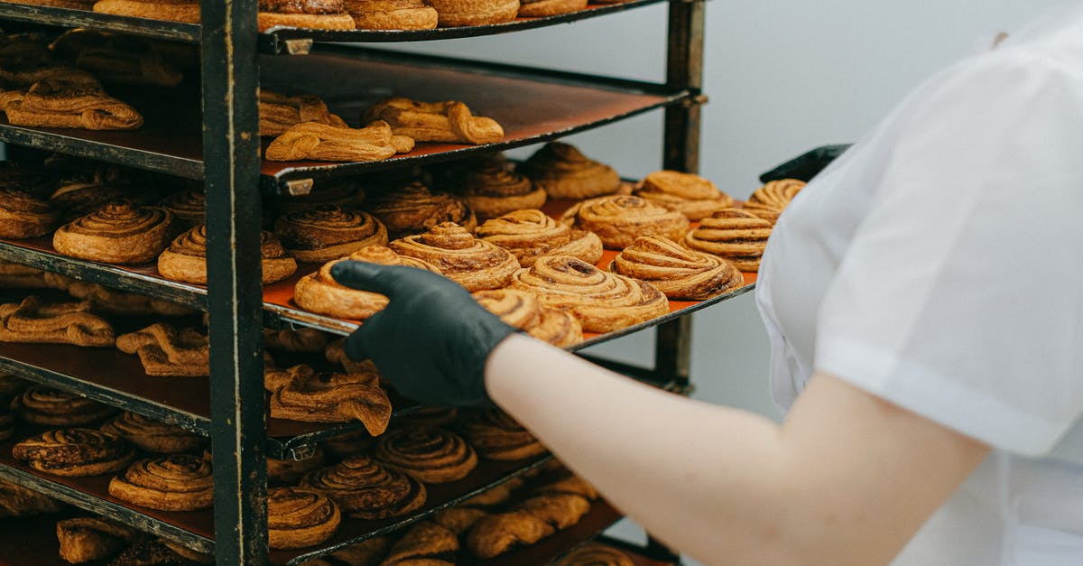 What does 'turn out' mean in bread baking? - Photo of a Person Taking Out a Tray of Cinnamon Rolls