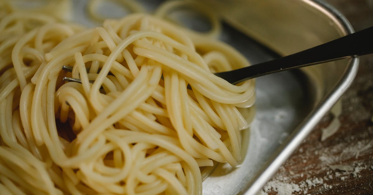 What does al dente really mean? - Cooked spaghetti and fork placed in steel bowl