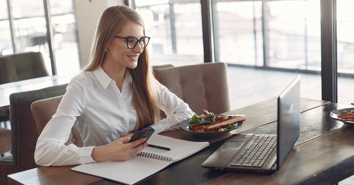What does it mean for a dish to be called poêlé? - Young cheerful businesswoman using smartphone and laptop in cafe during lunch time