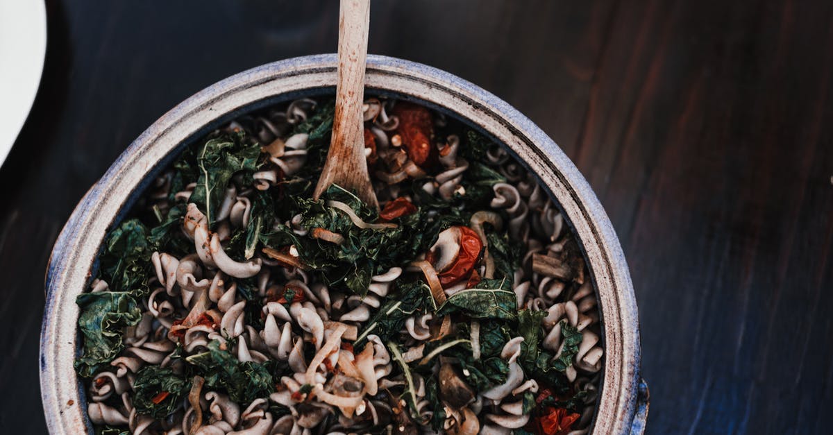 What does it mean when a dish or product is described as "(insert culture/tradition) style"? [closed] - Top view of appetizing fusilli mixed with spinach leaves and sun dried tomatoes in bowl with wooden spatula