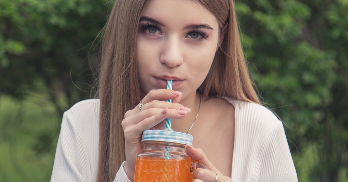 What does one use a saw for? - Woman in White Long Sleeve Shirt Holding Jar With Orange Liquid