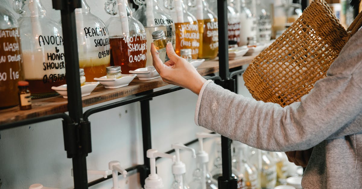 What everyday ingredient will emulsify rapeseed oil? - Crop customer examining glass jar with shampoo in market while standing near big dispensers placed on wooden shelves