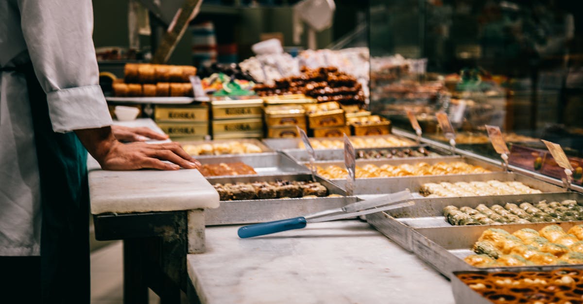 What factors should I consider when buying kitchen tongs? - Crop anonymous male seller at counter with assorted traditional Turkish sweets in market