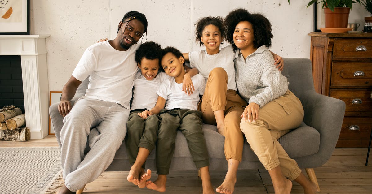 What features should I look for in a fireplace grill? - Full body of cheerful African American parents with children looking at camera while sitting on sofa in room with fireplace