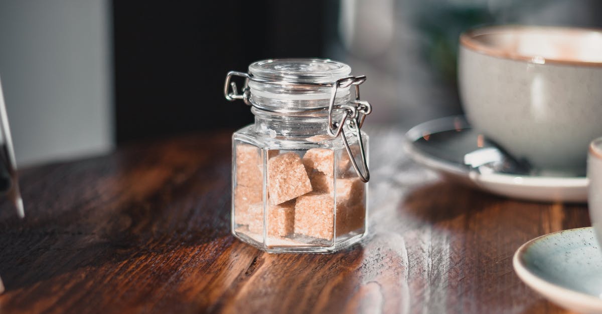 What food can contain a hot drink? - Clear Condiment Shaker With Brown Sugar Cubes Near Gray Teacup