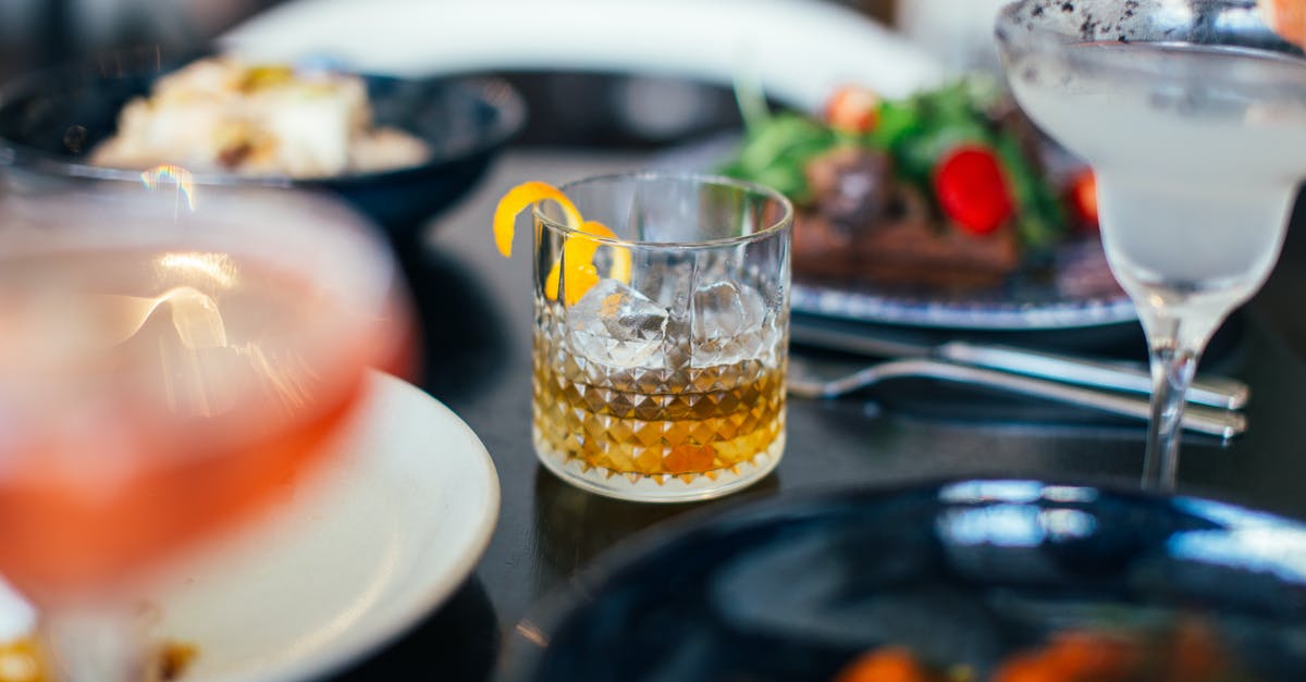 What happens if you freeze a soft serve of ice cream? - From above glasses of whiskey with ice cubes and lemon peel and vermouth with grapefruit placed on table near assorted dishes in restaurant