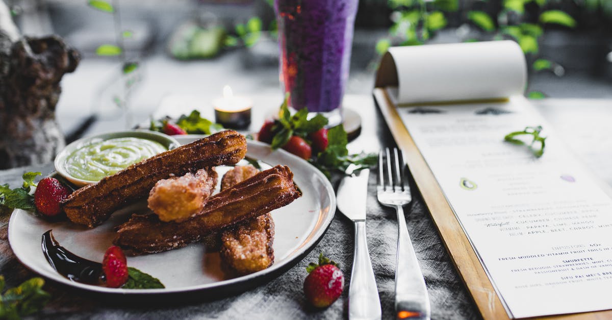 What ingredients do Bernaise sauce and fruit smoothies have in common? - Crispy sweet churros served with sauce and strawberries and placed on table near menu and fresh blueberry smoothie