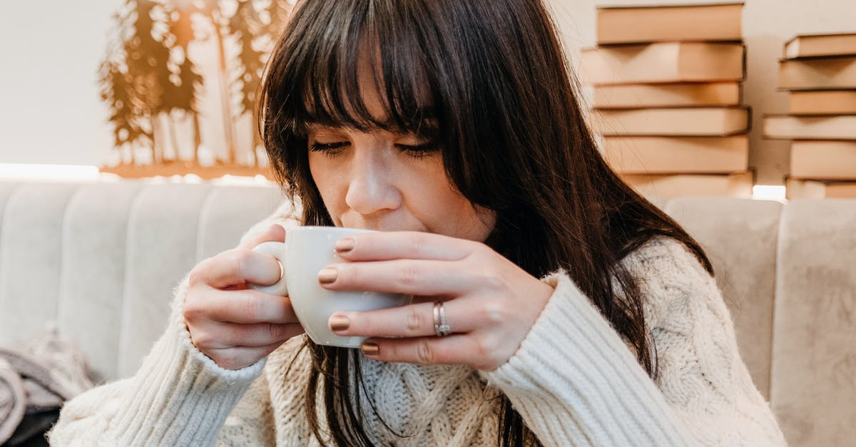 What is a reliable source for the caffeine content in tea? - Positive woman enjoying hot drink in cafeteria What is a reliable source for the caffeine content in tea? - Positive woman enjoying hot drink in cafeteria