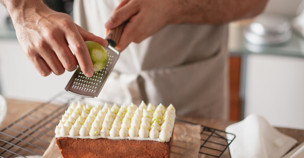 What is "Zest" - In particular: lime/lemon zest? - Close-up of a Person Grating Lemon Zest over a Cake