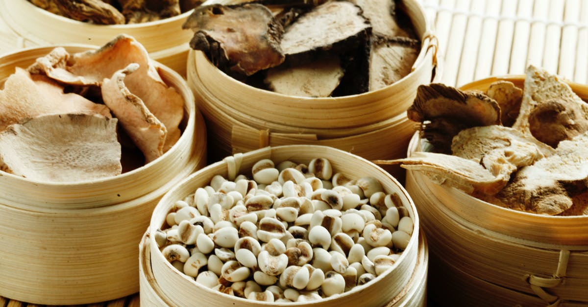 What is the best method of storage for condiments? - From above many wooden containers filled with assorted dried mushrooms with condiments and raw cashew nuts placed on bamboo mat