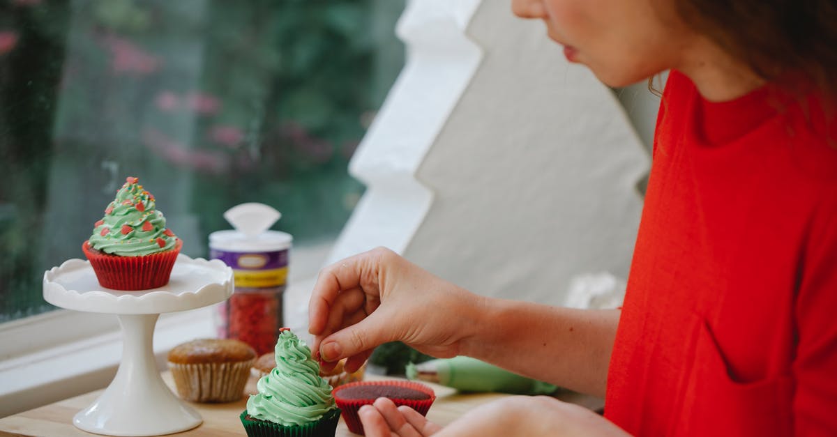 What is the best technique to put icing on plastic? - Side view of female cook putting sprinkles on frosting of cupcake while standing near window during holiday preparation at home