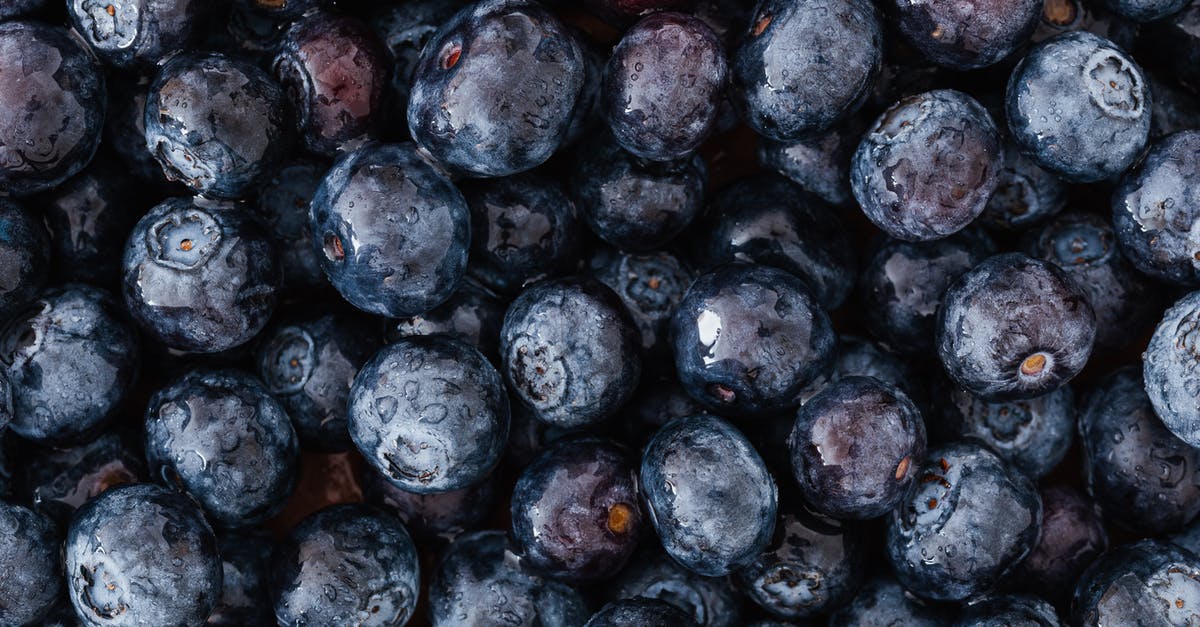 What is the best way to store fresh berries? - From above of appetizing fresh blueberries different sizes arranged even layer on grocery store stall