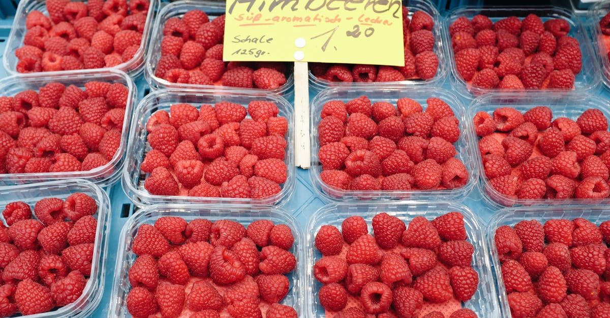 What is the best way to store fresh berries? - Plastic containers with fresh raspberries on market stall