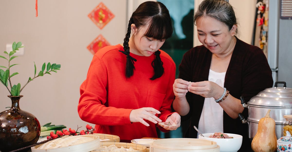 What is the boundary between beef aging and its decay? - Cheerful Asian grandma with granddaughter filling dough while cooking dim sum at table with steamer and fresh squash
