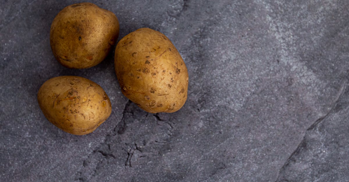 What is the conversion ratio from whole potatoes to potato flakes? - Top view of whole unpeeled potatoes placed on rough gray marble table in kitchen