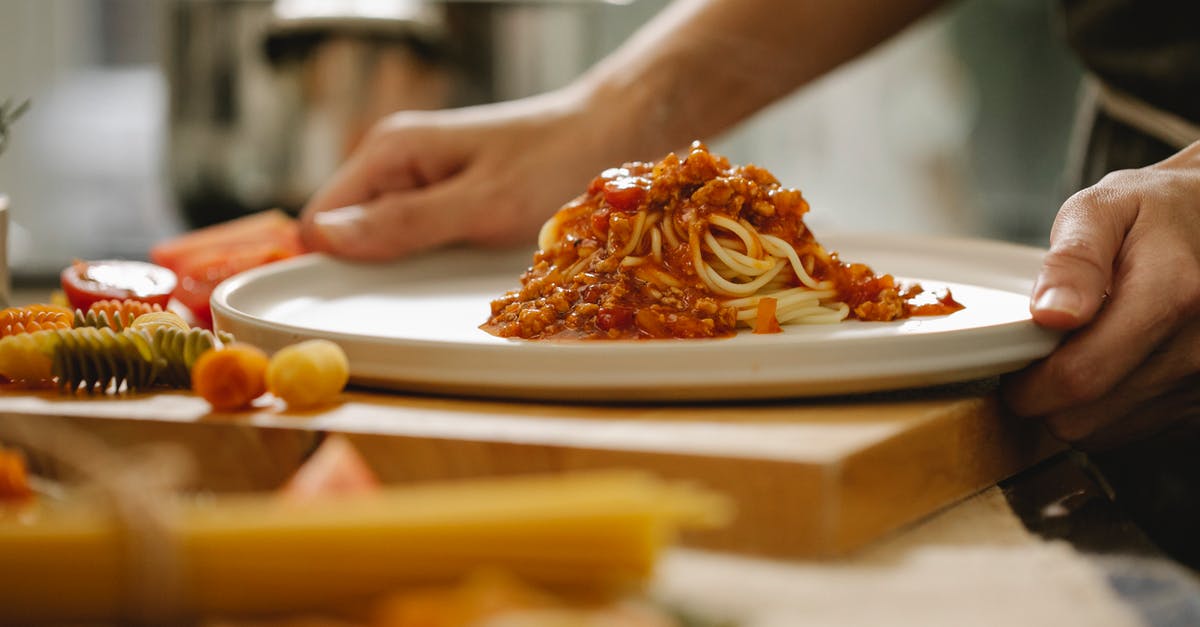 What is the correct timing when cooking spaghetti sauce from minced meat and prepared tomato sauce? - Cook taking plate with pasta Bolognese in kitchen