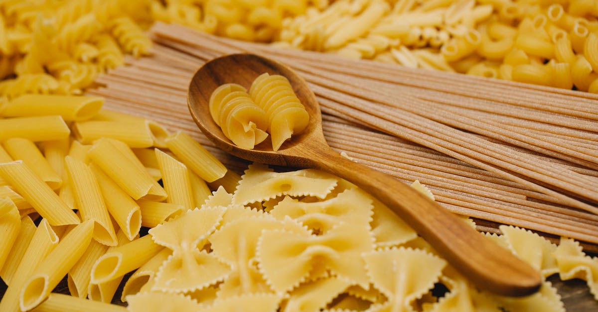 What is the difference between cracked wheat and wheatgerm? - Different types of raw pasta with wooden spoon