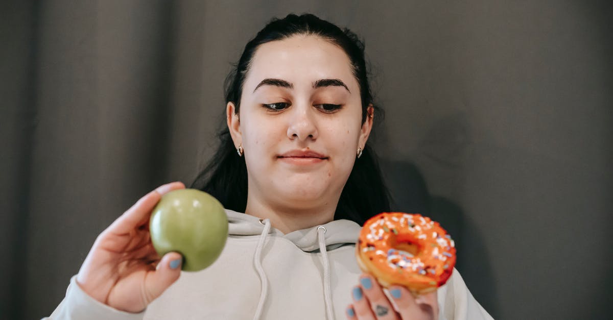 What is the difference between doughnut and krapfen? - Positive woman choosing between donut and apple