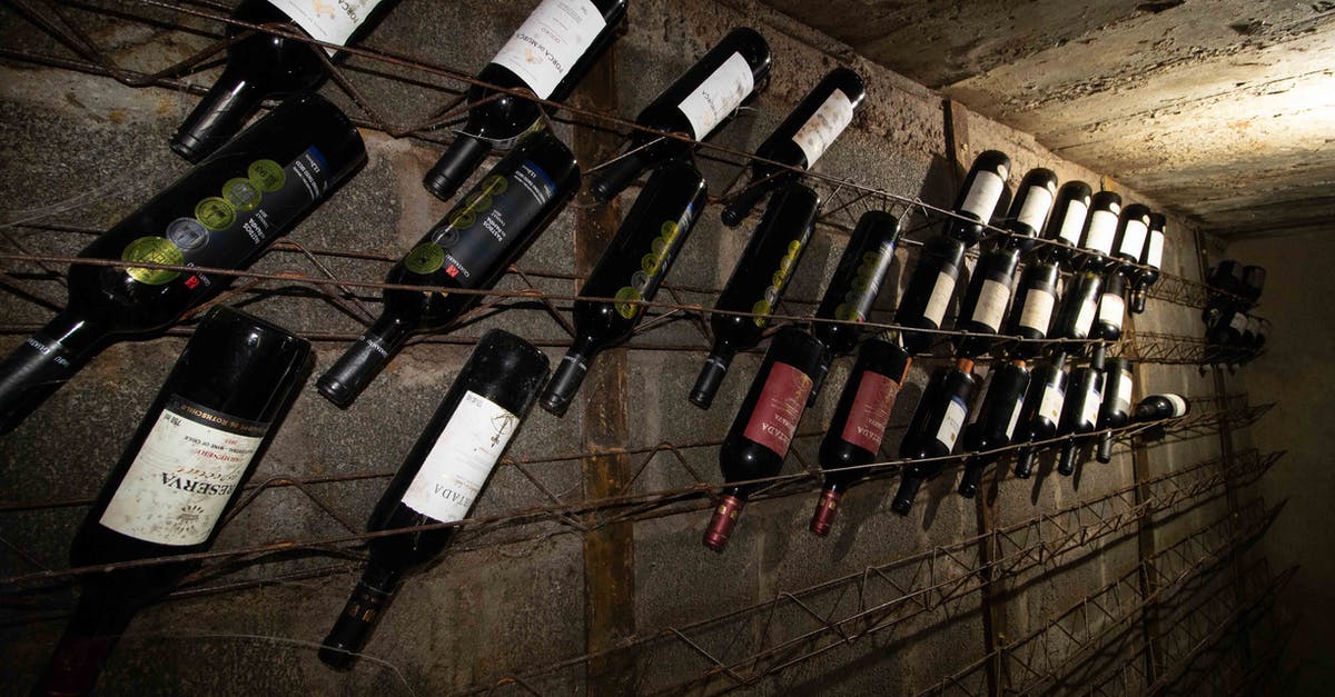 What is the difference between expensive wine and regular wine? - Rows of glass bottles filled with various wine in cellar with gray concrete walls