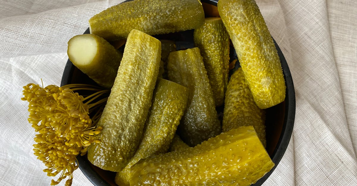 What is the difference in flavor between a fermented pickle and a vinegar pickle? - Sliced Green Fruits on Black Ceramic Plate