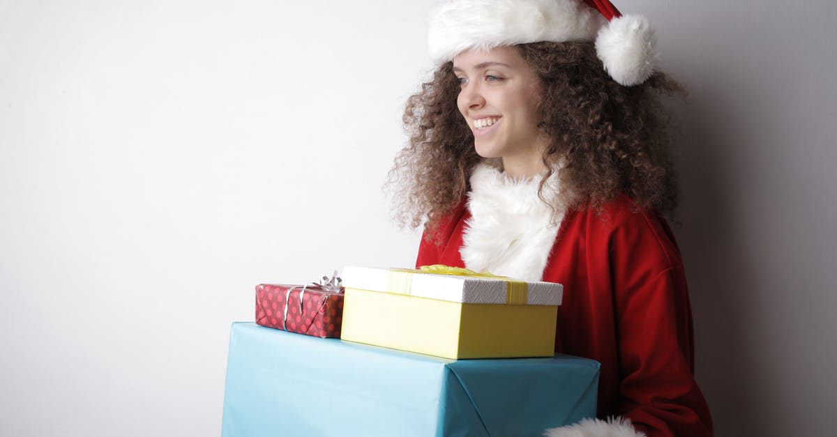 What is the magic in packaged pudding mixes? - Side view of cheerful female with curly hair wearing Santa hat and costume standing with stack of wrapped presents on white background in studio and looking away