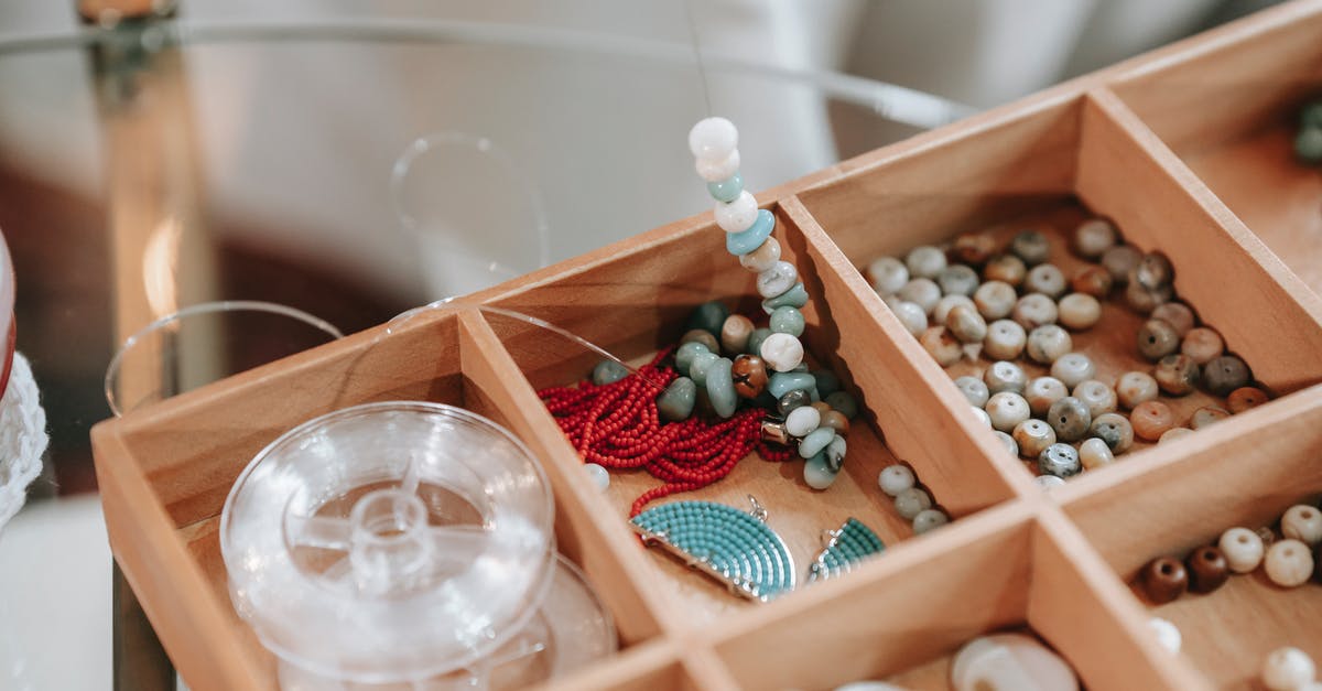 What is the name of the tool which involves a ball inside a sealed container that is shaken to grind up spices? - Wooden container with abundance of colorful beads and elastic cord for making bracelet placed on glass table in light room