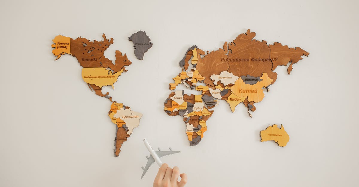 What is the name of this Turkish chocolate? - Crop unrecognizable person with toy aircraft near multicolored decorative world map with continents attached on white background in light studio