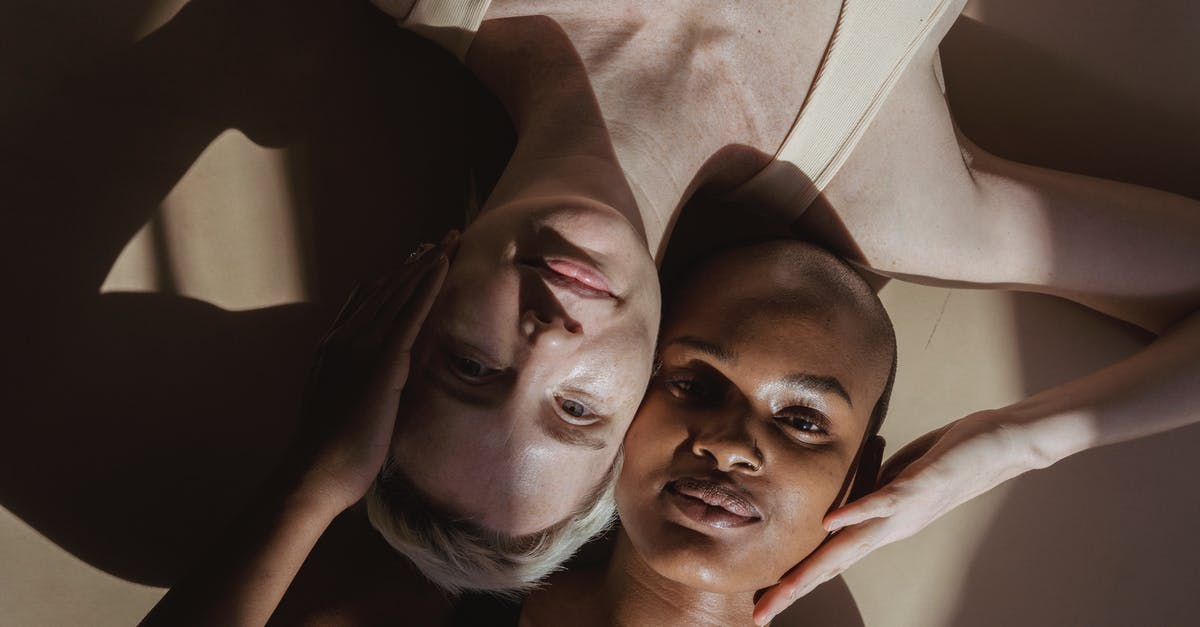 What is the opposite of cuvée? - Top view of smiling multiethnic female models without makeup lying on gray surface and touching heads holding hands on face while looking at camera with shadows on face