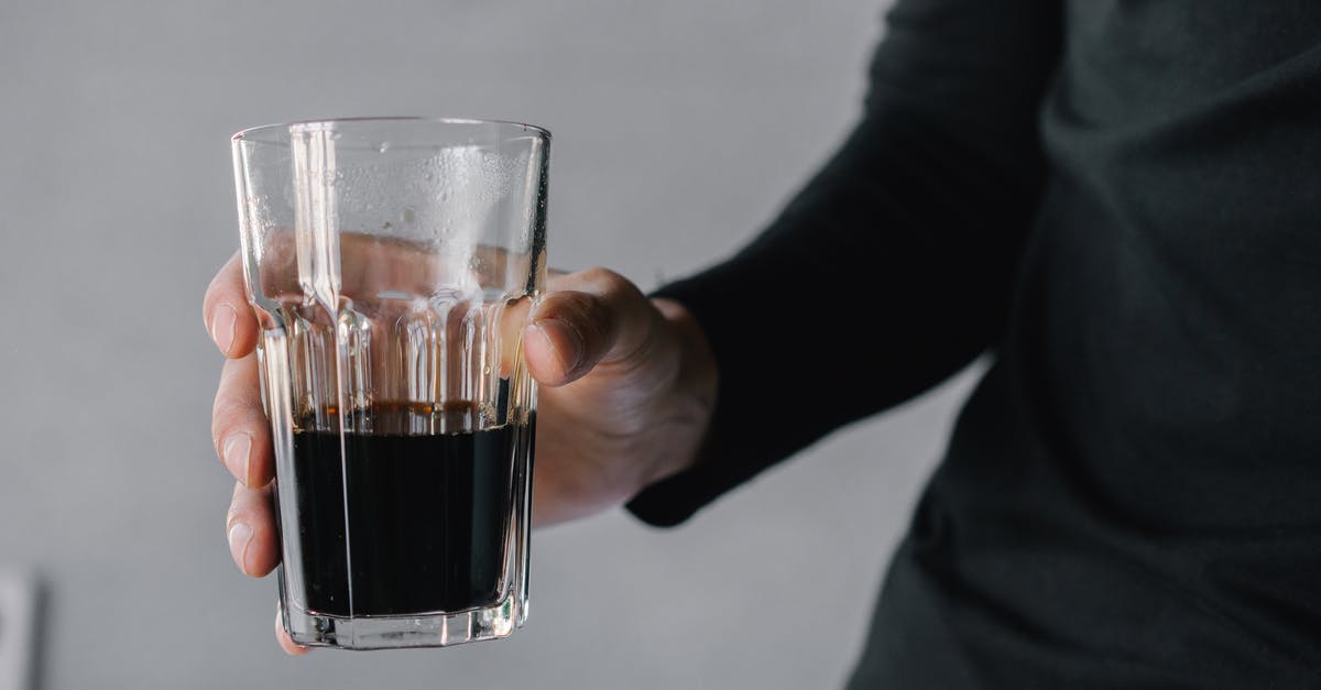 What is the optimal steep time for cold-brewed coffee? - Person Holding Clear Shot Glass With Black Liquid