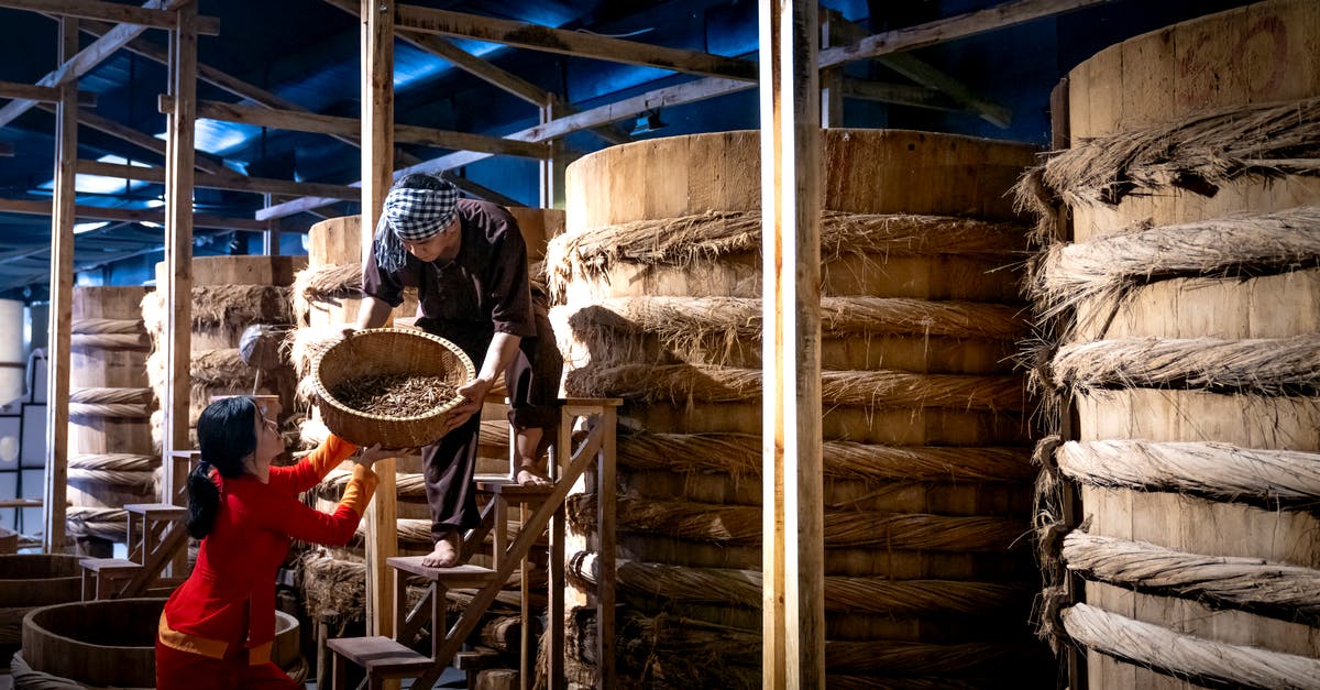 What is the origin of fish sauce in asia? - Workers near barrels in fish sauce factory