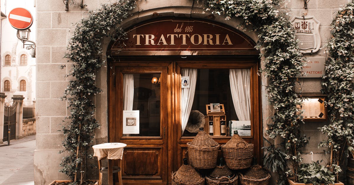 What is the place called where cheese is aged? - Exterior of cozy Italian restaurant with wooden door and entrance decorated with plants