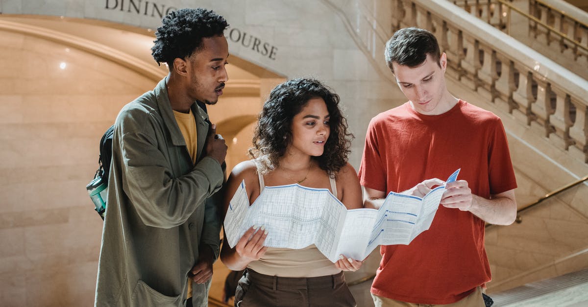What is the point of a "Friendship Bread" starter? - Focused young man pointing at map while searching for route with multiracial friends in Grand Central Terminal during trip in New York