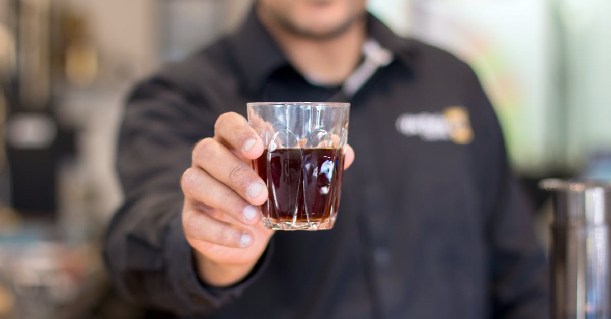 What is the proper serving temperature for Turkish coffee? - Selective Focus Photo of Man's Hand Holding Drinking Glass With Liquid Inside