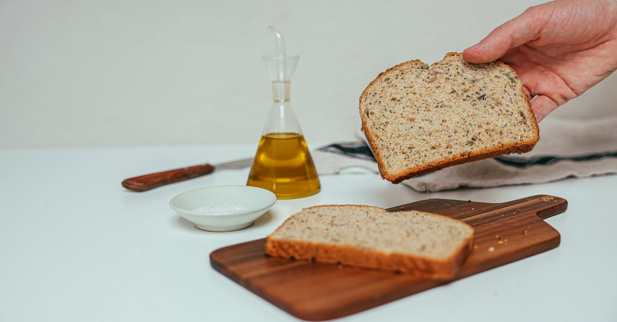 What is the purpose of oiling a wooden chopping board? - A Person Holding a Slice of Bread Beside a Dispenser with Yellow Liquid