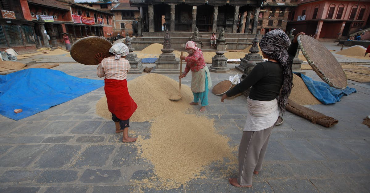 What is the purpose of sifting dry ingredients? - Anonymous ethnic female in traditional wear sifting rice with sieves on square against old city buildings