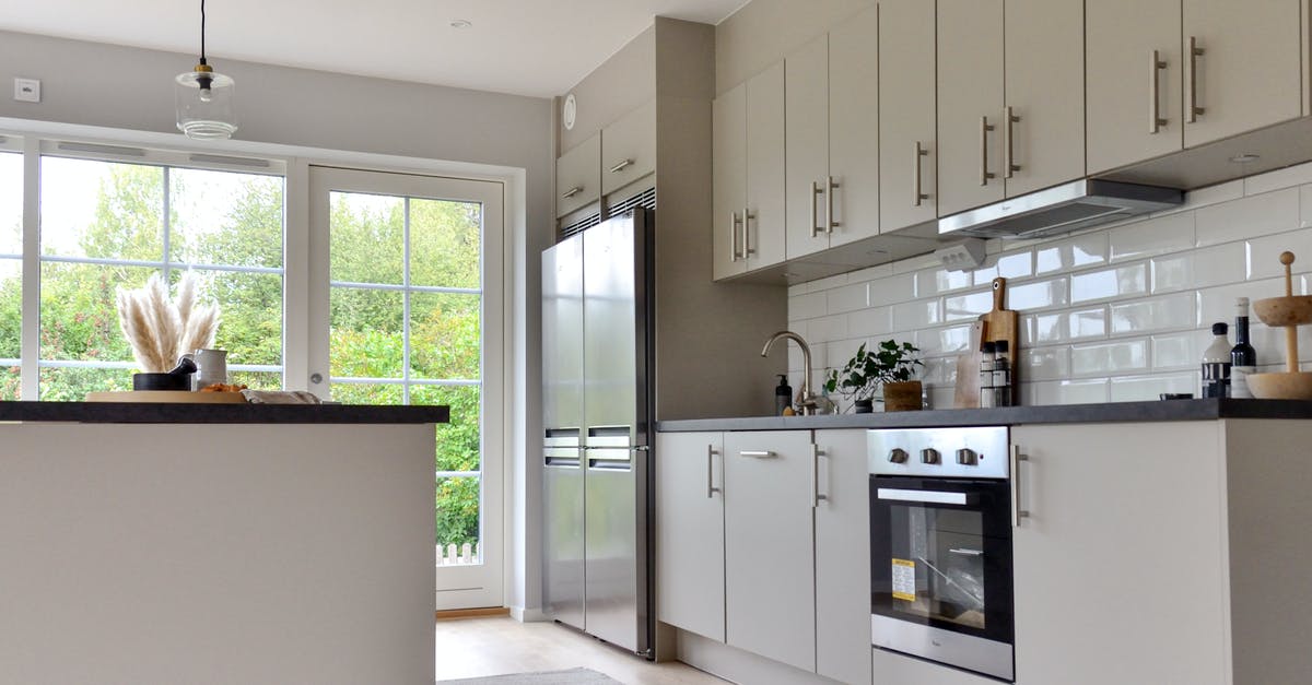 What is the purpose of the storage beneath an oven? - Minimalist white furniture and modern stainless steel appliances in stylish kitchen at home on sunny day