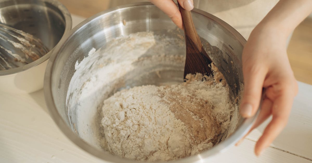 What is the rule of thumb for mixing doughs? - A Person Mixing the Dough Using a Wooden Spatula in a Stainless Bowl