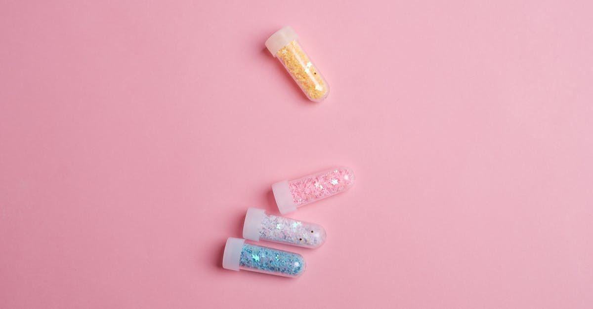 What is the science behind Magic Cake? - Top view of glass tubes filled with colorful sparkling star shaped glitter scattered on pink table